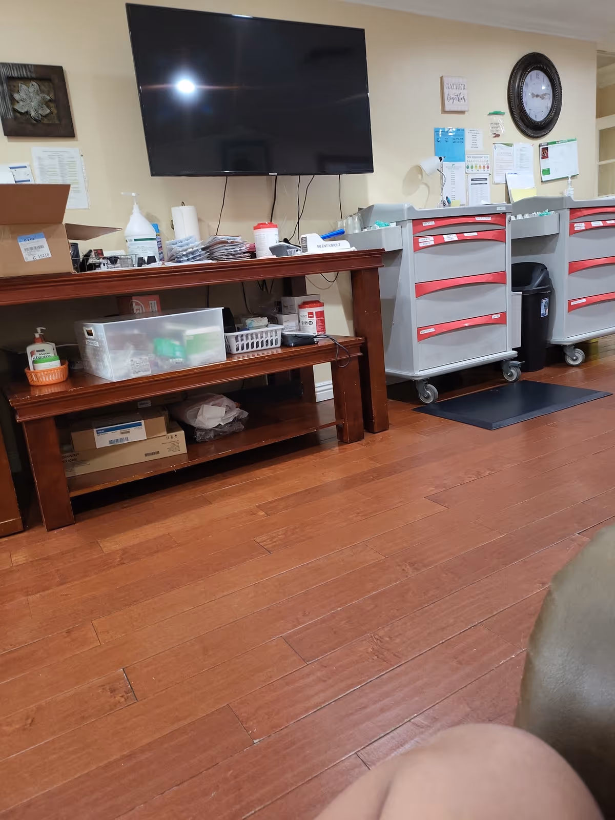 Nursing station area with a mounted TV, carts, and supply shelves.