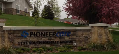 Stone sign reading PioneerCare Center with landscaping and a building entrance in the background.