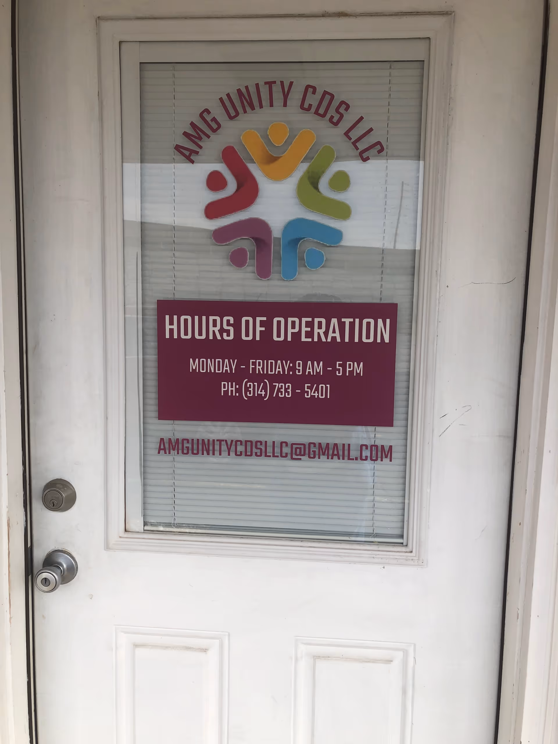 White exterior door with window sign for AMG Unity CDS LLC and hours of operation.