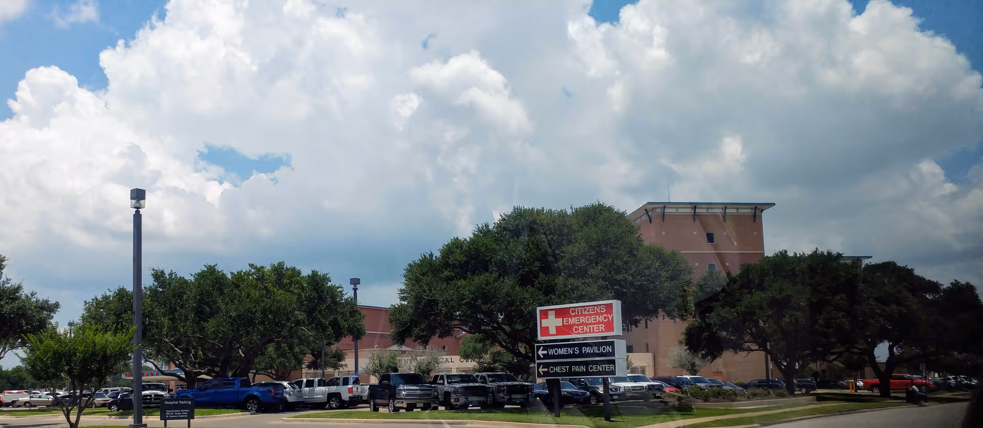 Exterior view of Citizens Medical Center with a parking lot, trees, and a sign.