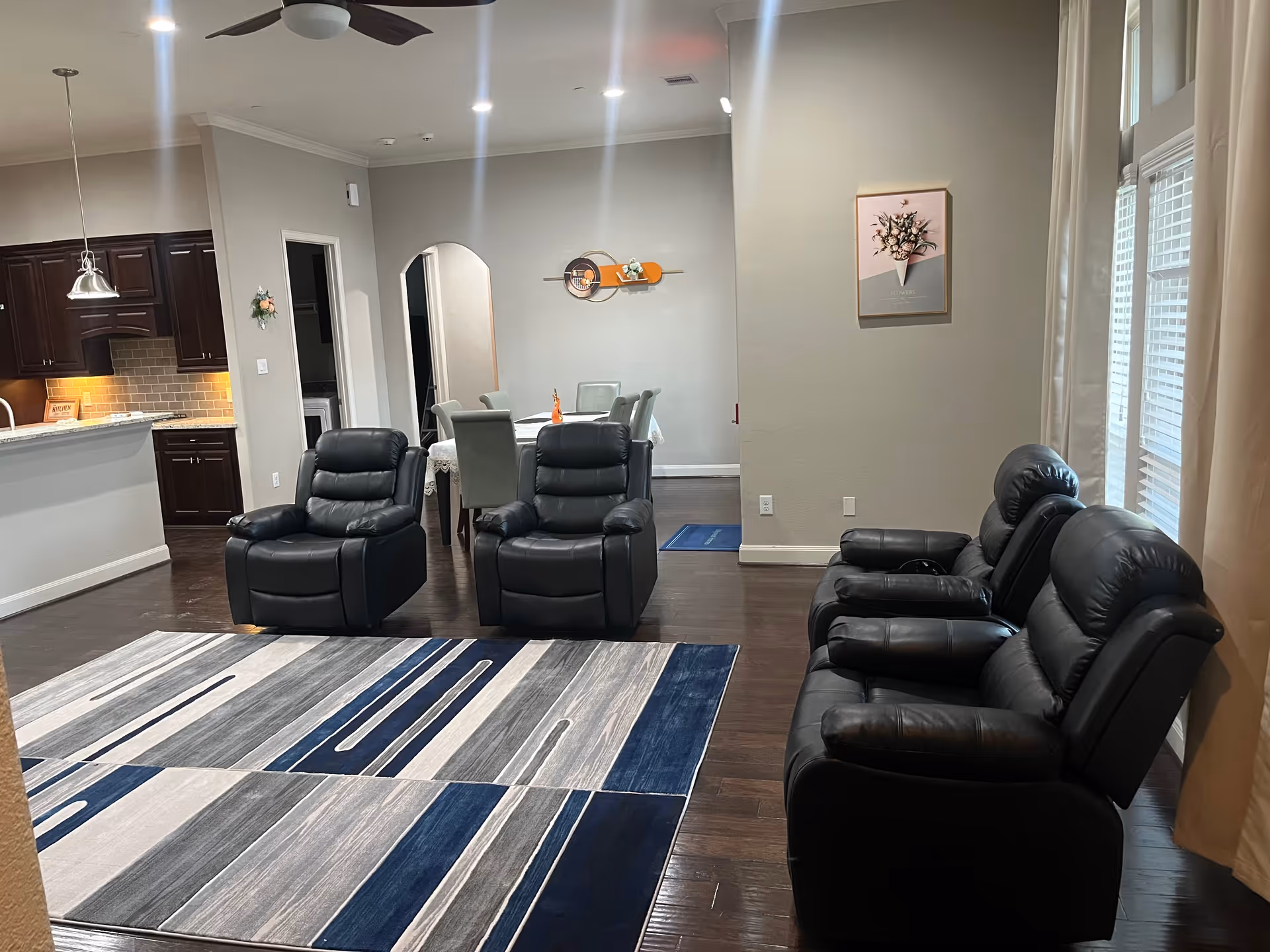 Common living room with leather recliners, a dining table, and kitchen visible in background.