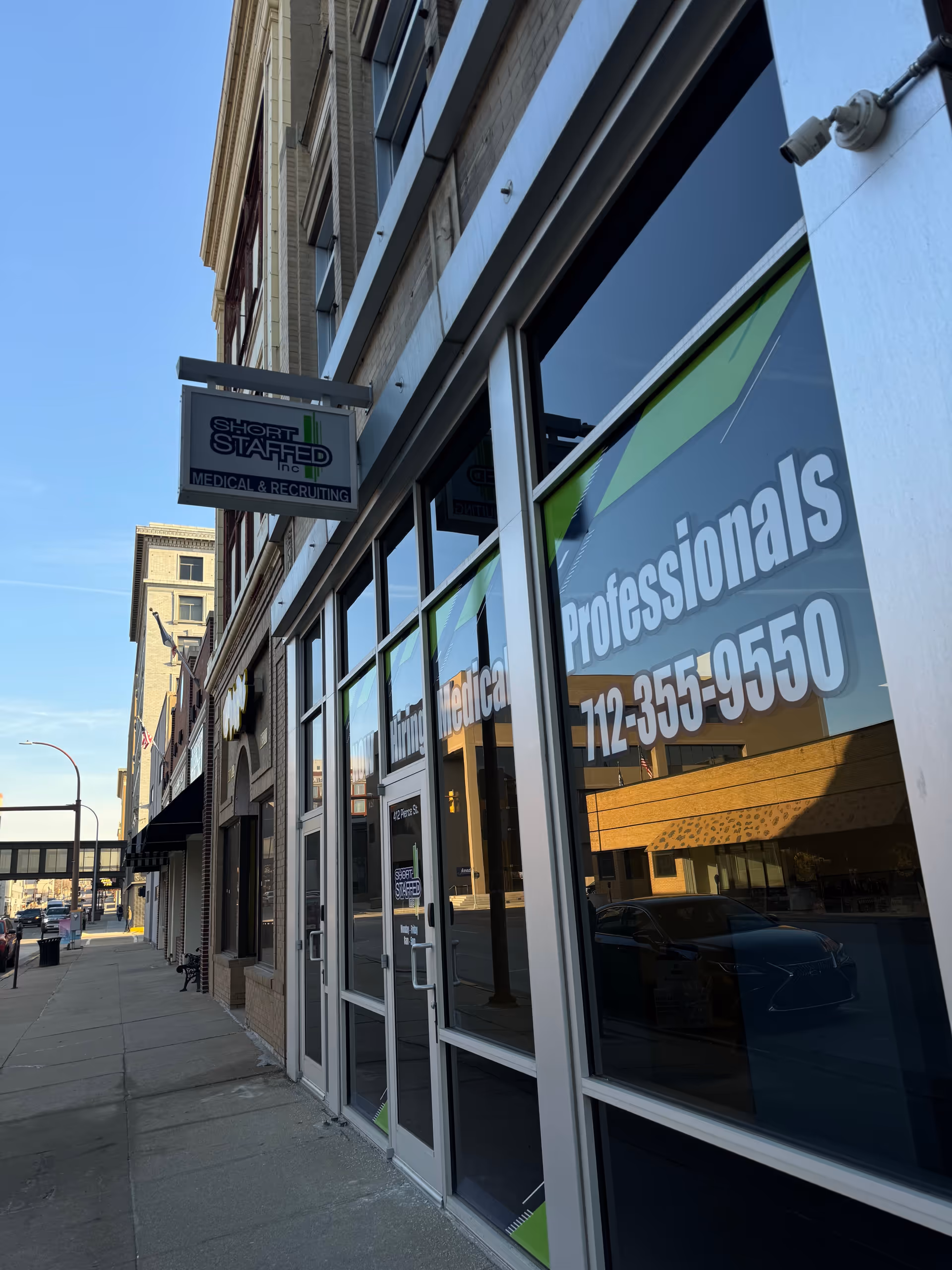 Exterior storefront with Short Staffed Inc signage and large window graphics.