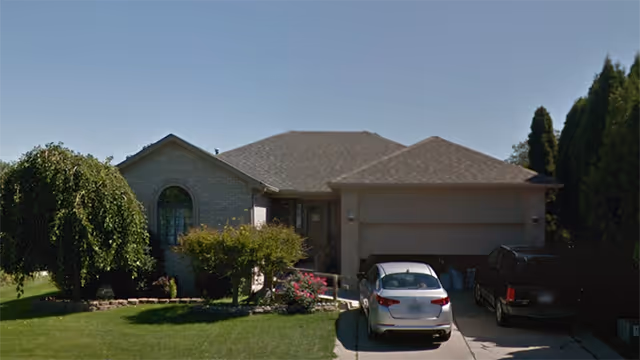 Front view of a single-story brick building with two cars in the driveway.