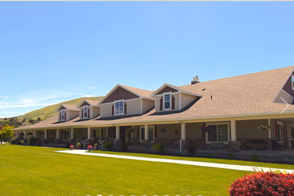 Exterior view of The Gables Assisted Living of Pocatello, with porch and lawn.