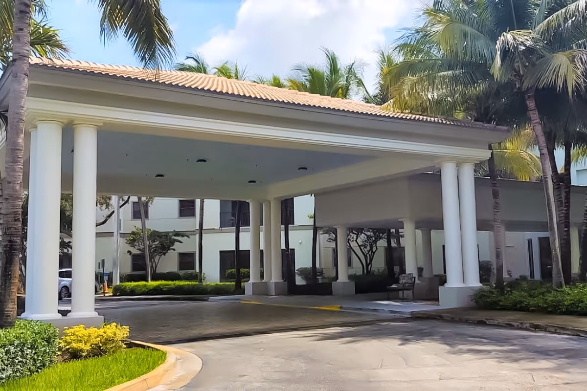 Covered entrance with white columns and palm trees at Verena at Delray.