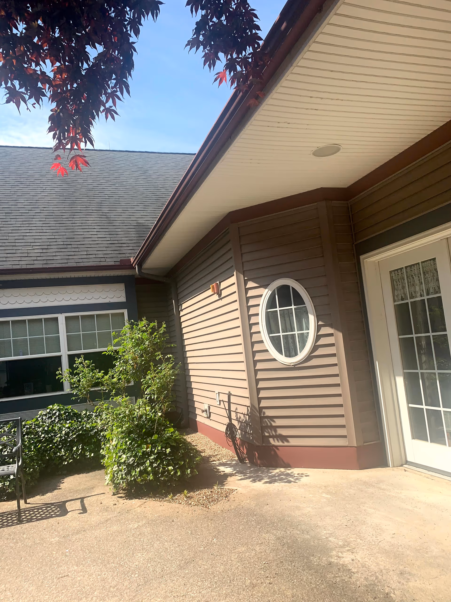 Exterior of Caretel Inns of St. Joseph with beige siding, round window, and greenery.