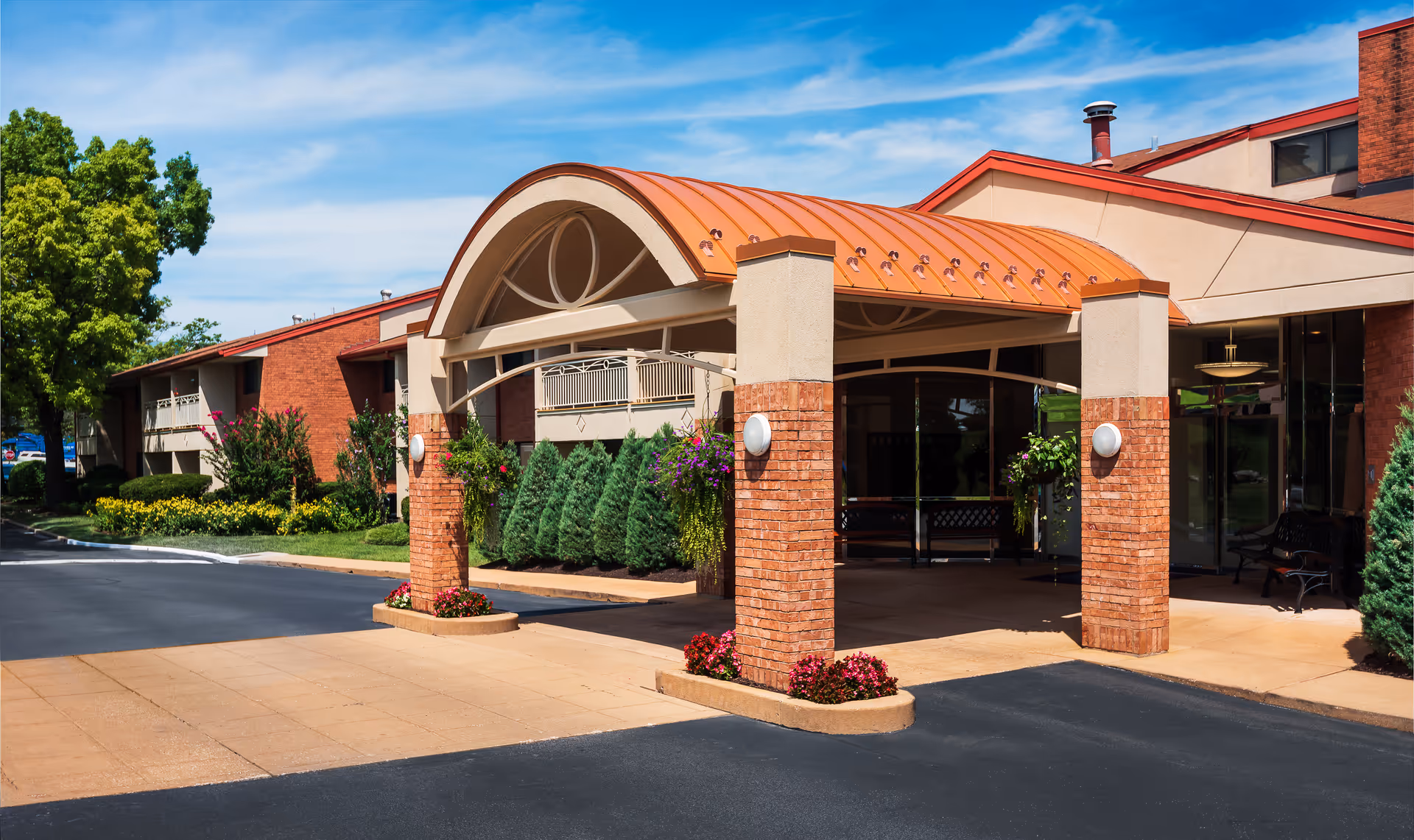 Exterior view of Garden Villas facility entrance with brick columns and orange arched canopy.