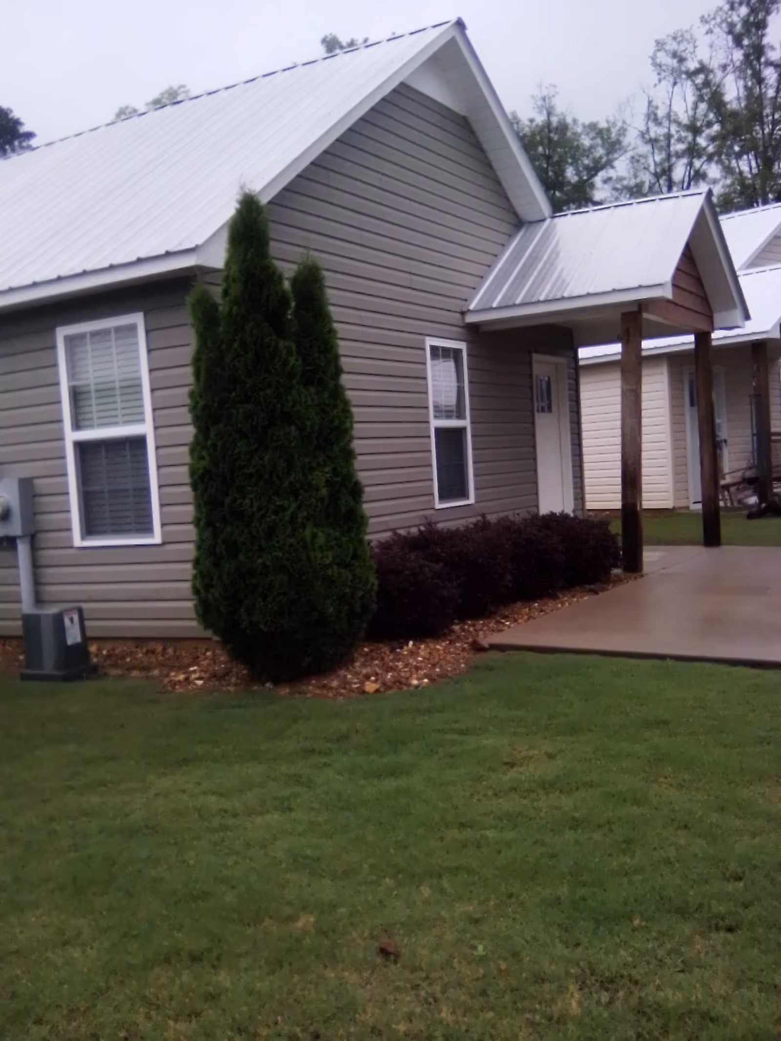 Single-story facility with gray siding, white trim, small front porch, and green lawn.