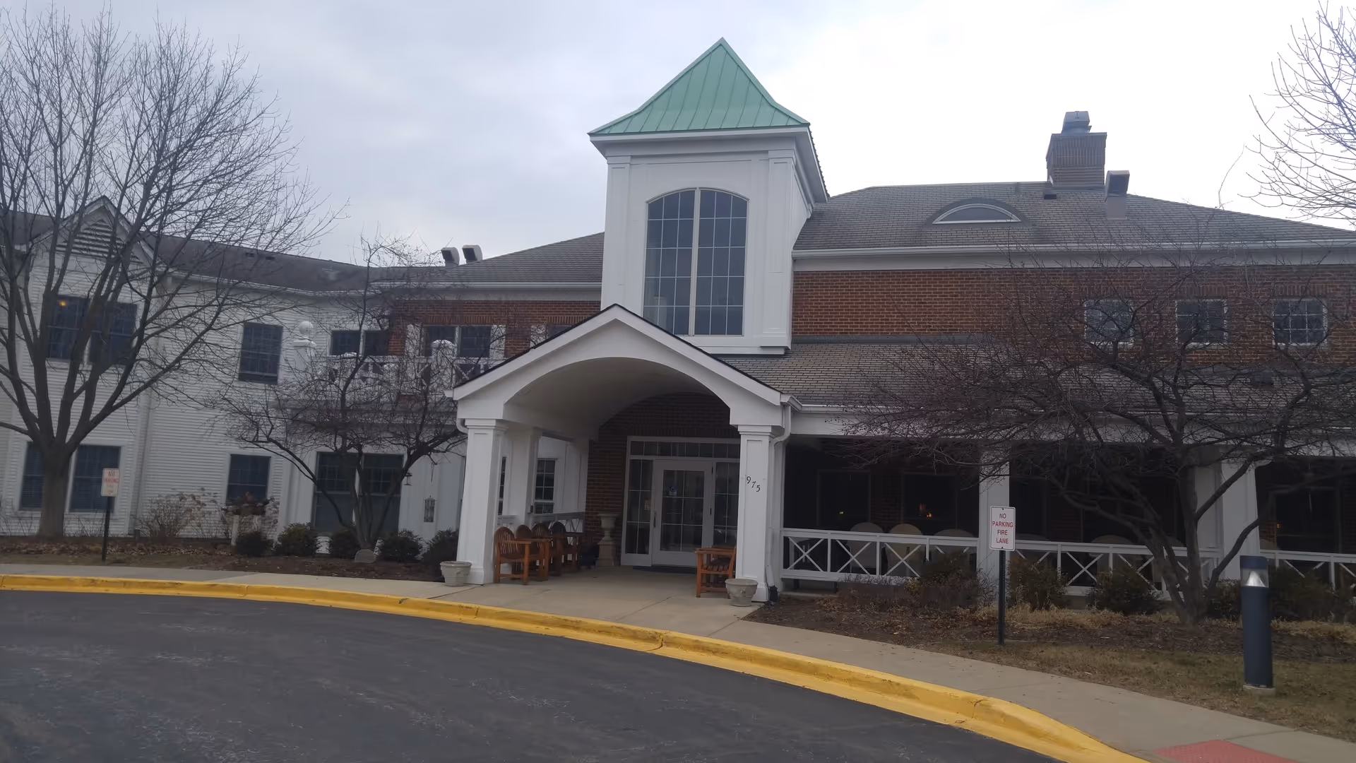 Front view of River Glen of St. Charles building entrance with benches and covered entry.