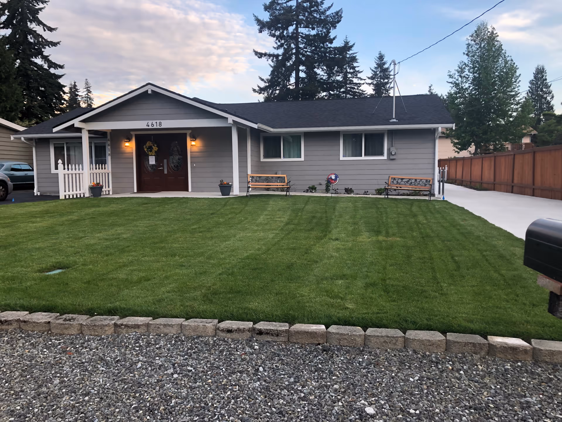 Front view of a single-story gray building labeled 4618 with a manicured lawn and benches.