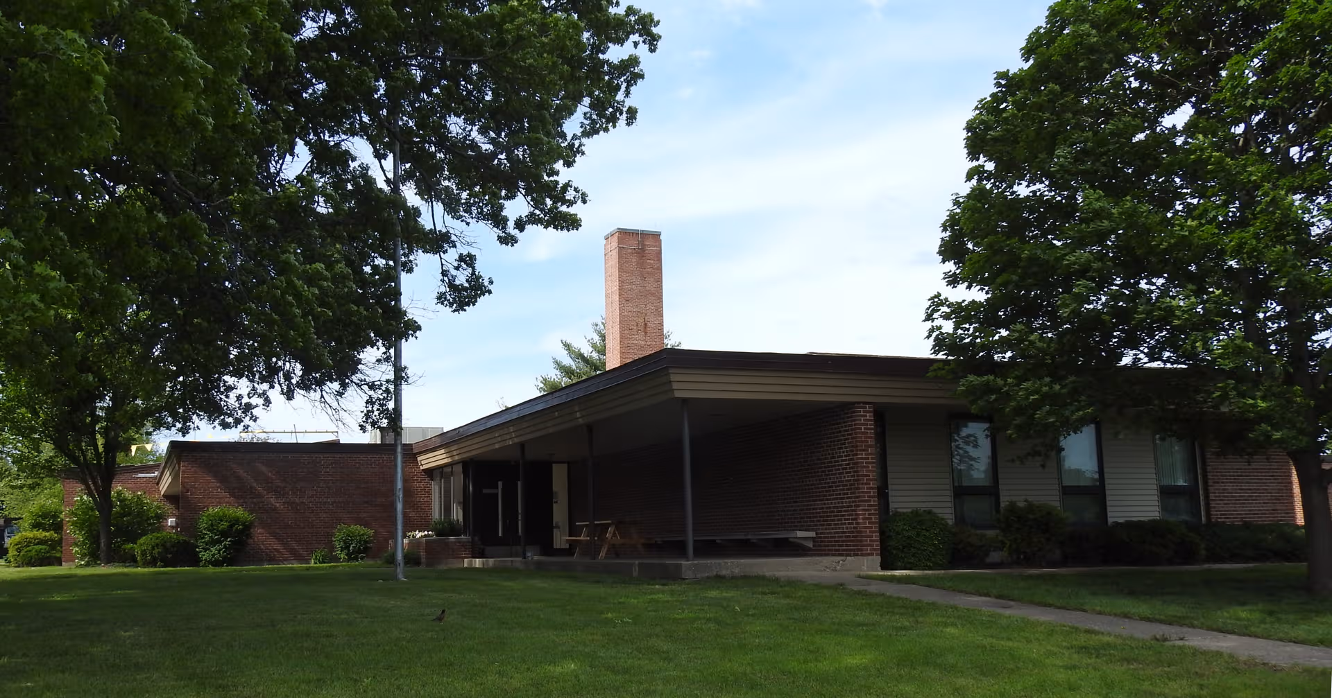 Single-story brick senior living facility with a covered entrance and green lawn.