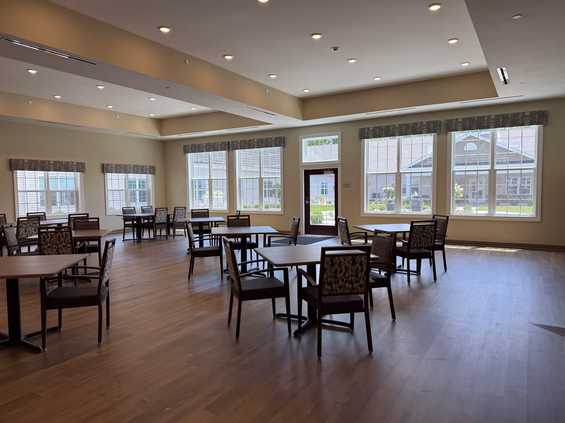 Spacious dining room with multiple tables and chairs by large windows.