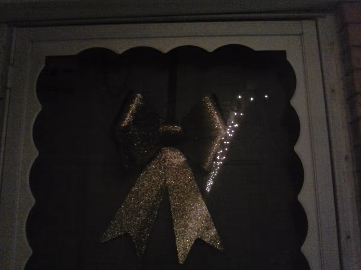 Doorway with a large glittering gold ribbon decoration on a dark exterior.