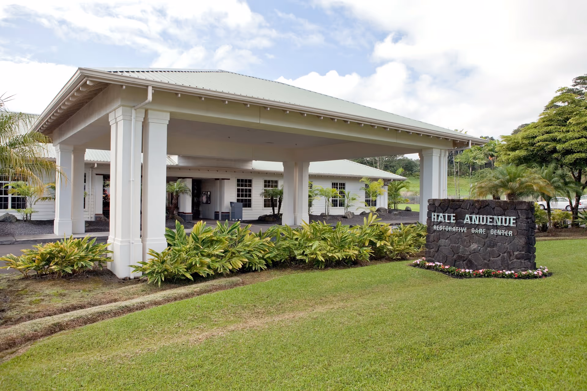 Exterior view of Hale Anuenue Restorative Care Center entrance with landscaping.