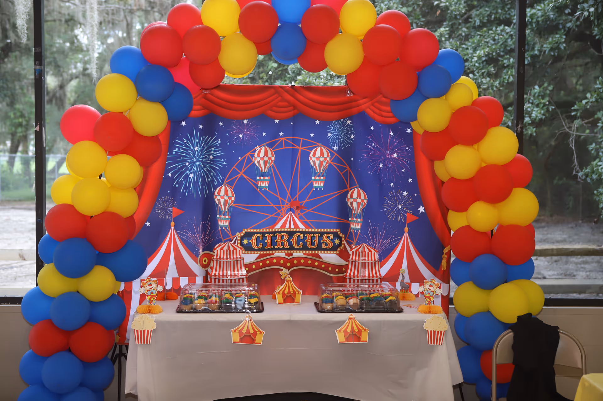 Indoor circus-themed party setup with colorful balloon arches and a dessert table.
