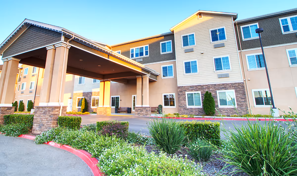 A multi-story senior living building with a covered entrance and landscaped grounds.