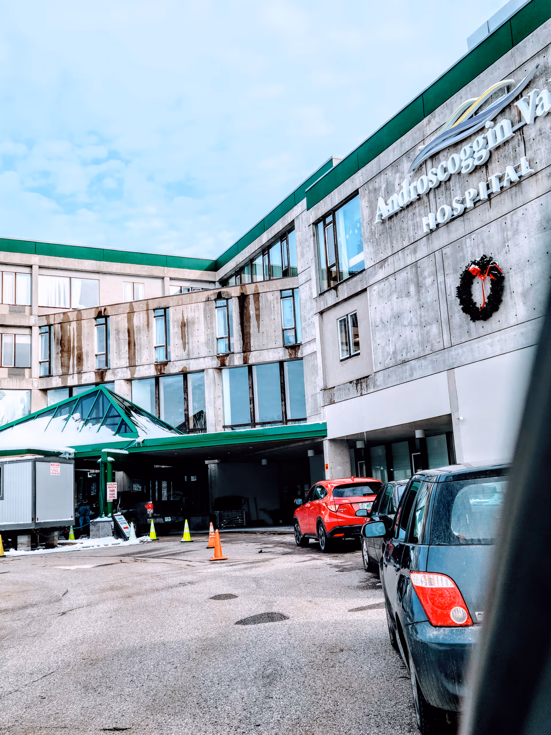 Exterior front view of Androscoggin Valley Hospital with cars in the driveway.