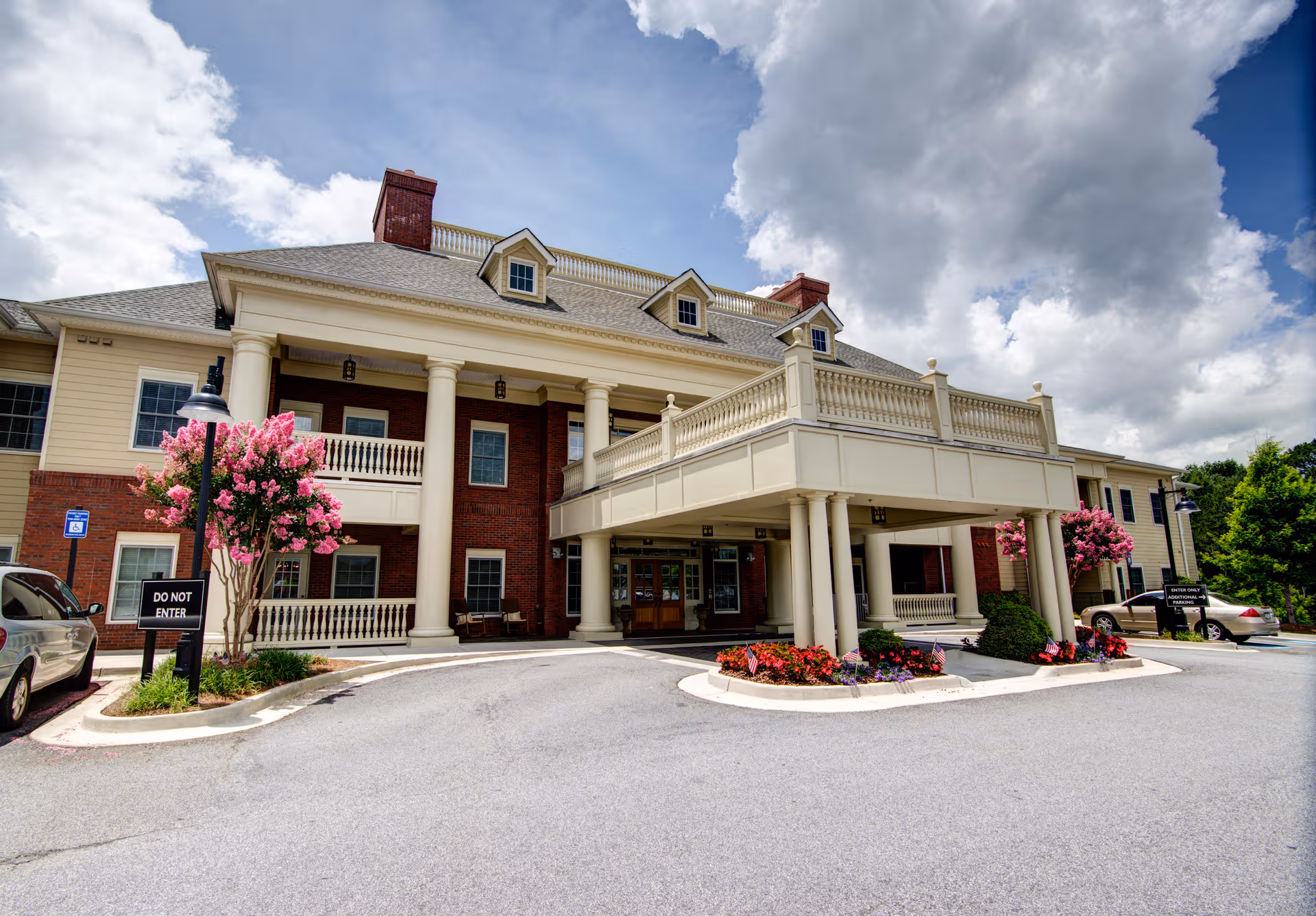 Front exterior of Gardens of Gainesville senior living building with columns and landscaped entry.