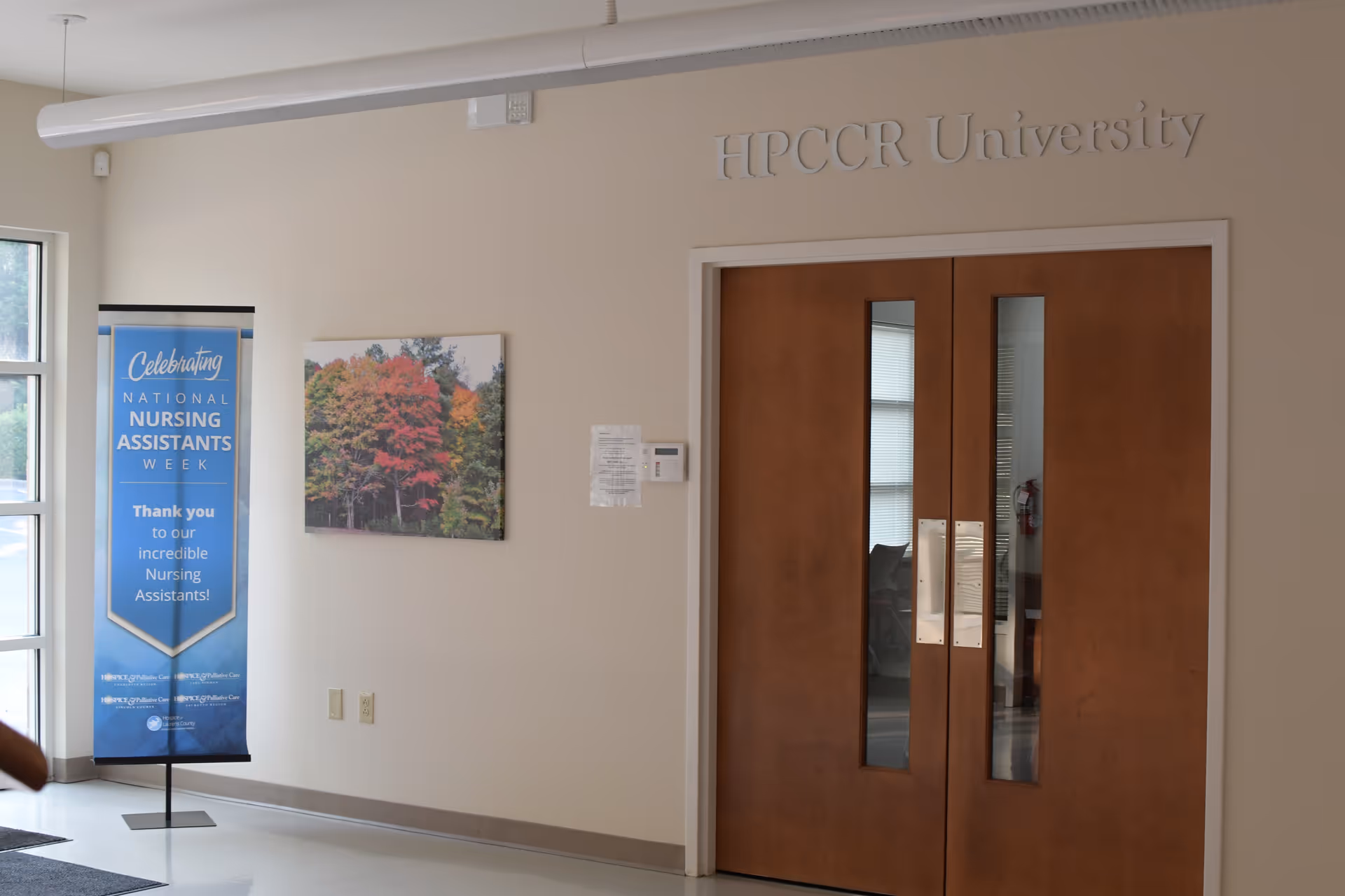 Interior hallway with double wooden doors and a nursing banner.