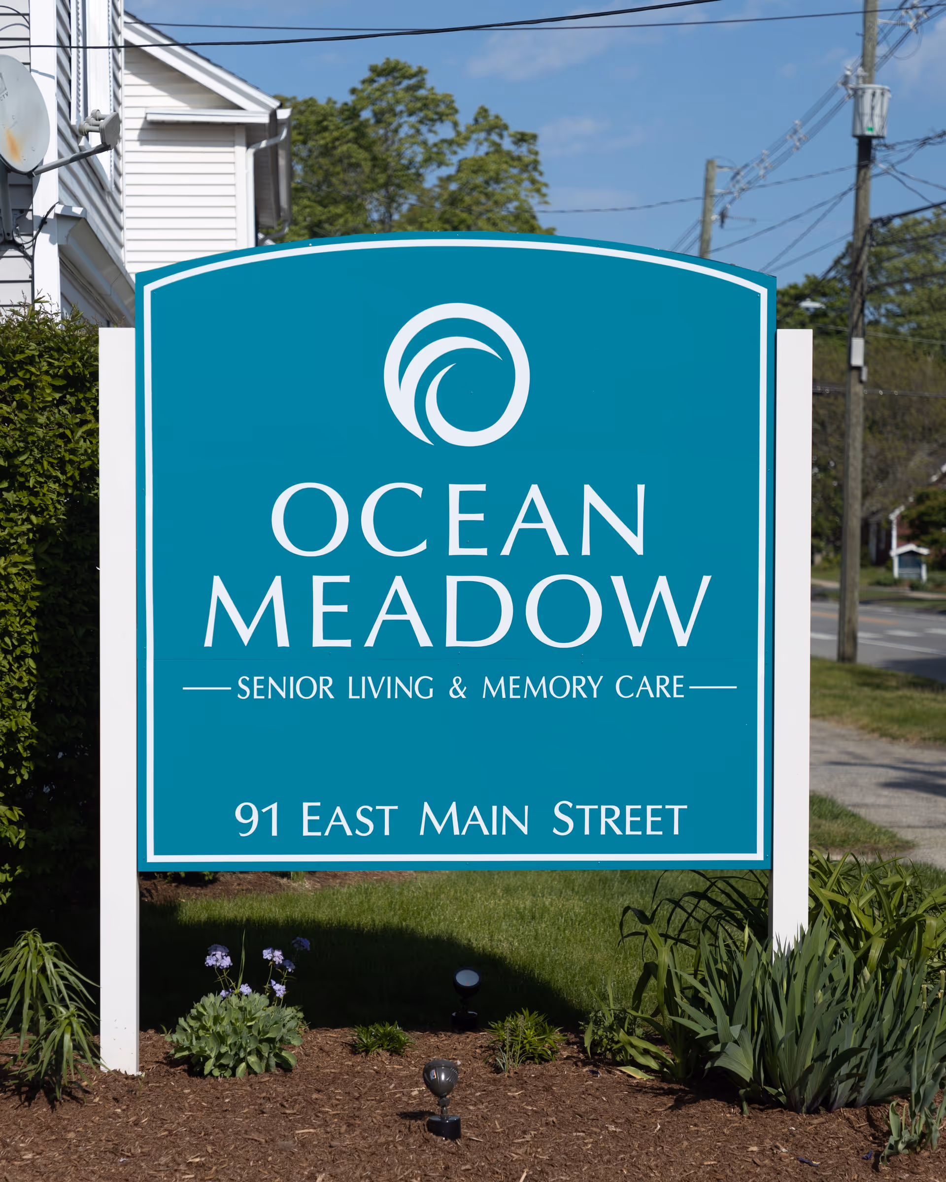 Teal Ocean Meadow sign advertising senior living and memory care in front yard.