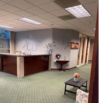 Reception area with CLT at Home logo, curved front desk, and hallway leading to rooms.