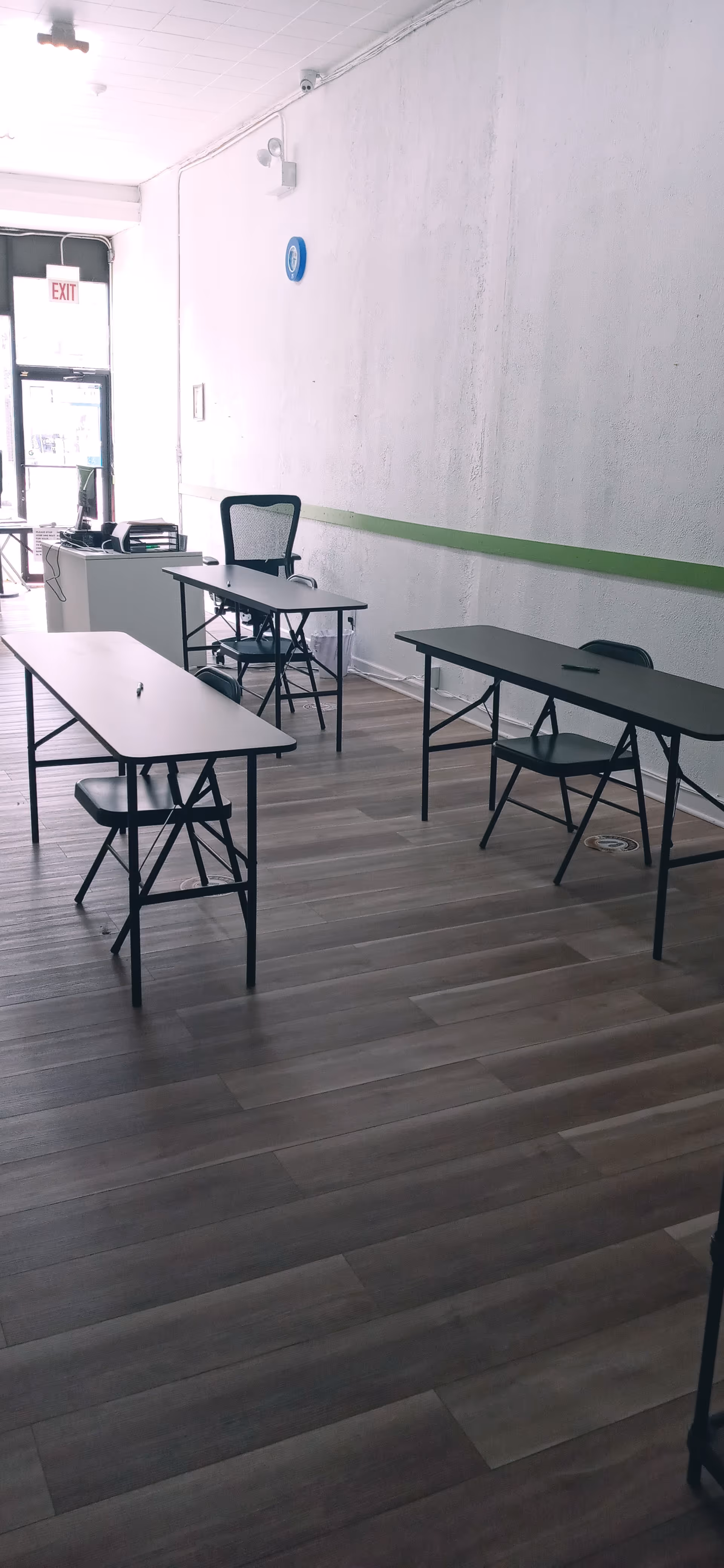 Empty interior room with folding tables and chairs arranged along the wall.