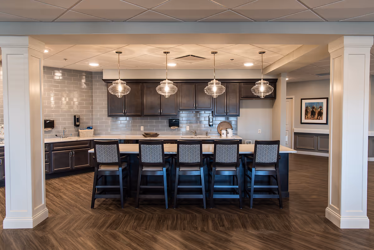 Modern communal dining area with a long kitchen island and pendant lights.