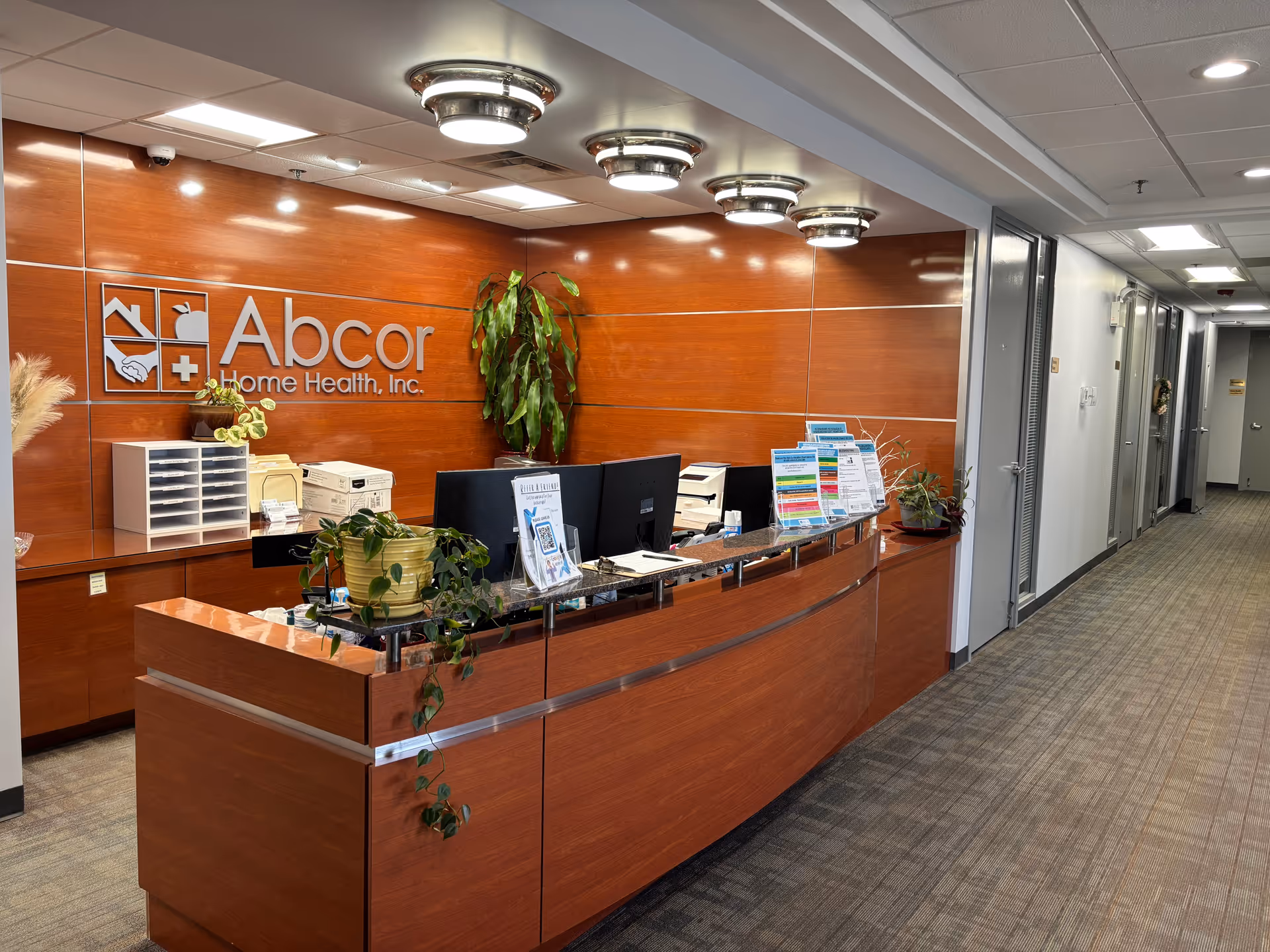 Reception desk in a wood-paneled hallway with Abcor Home Health logo.