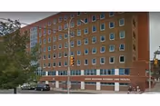 Red brick multi-story building labeled Queens Boulevard Extended Care Facility on a city street.
