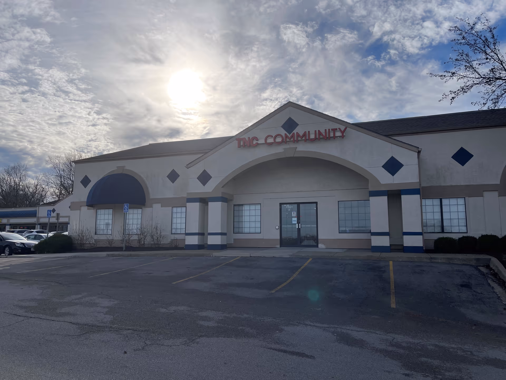 Exterior view of a TNC Community building with a parking lot in front.