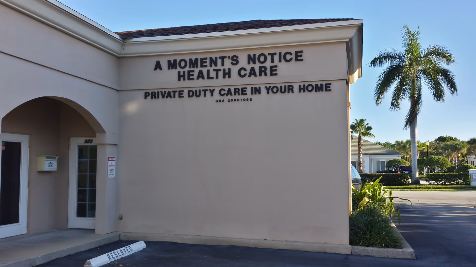Exterior view of A Moment's Notice Health Care building with palm trees and signage.
