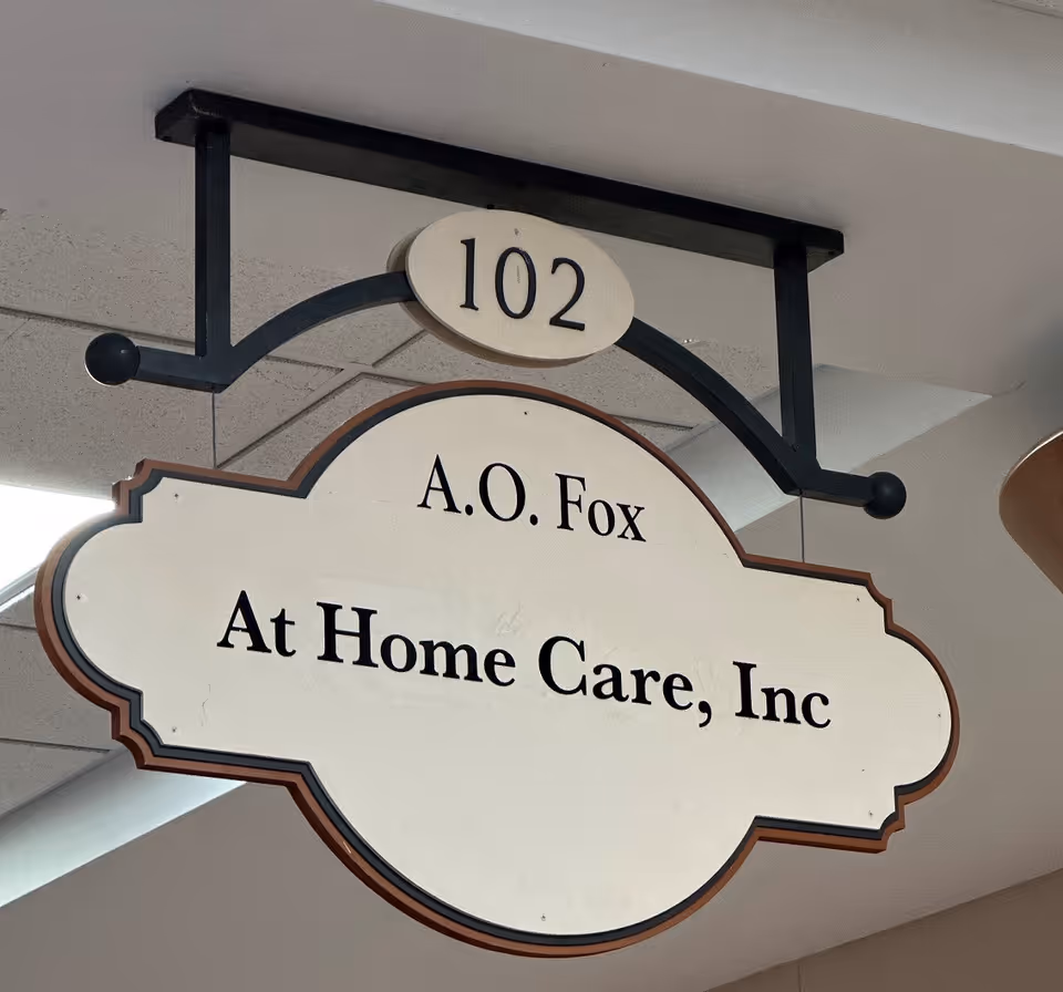 Hanging interior sign displaying A.O. Fox At Home Care, Inc with room 102.