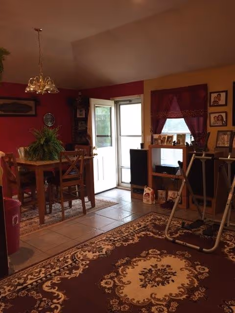 Interior dining area of a senior home with a wooden table, chairs, and rug.