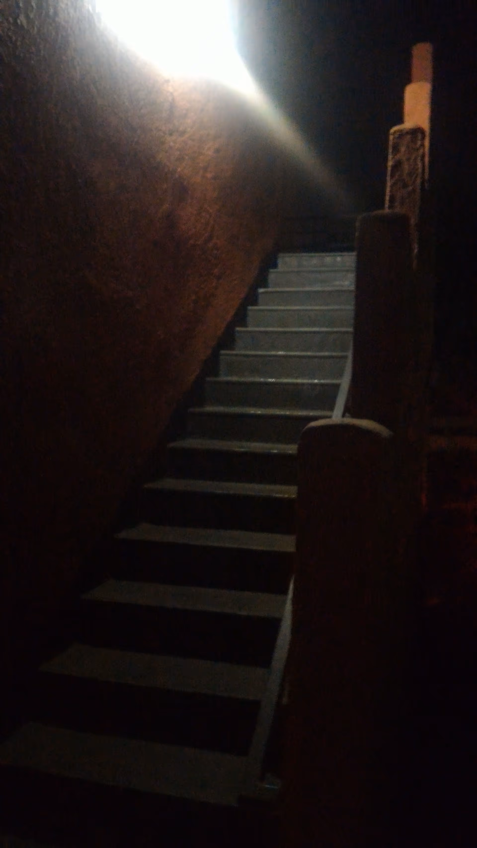 Dim stairwell with concrete steps and a bright light at the top.
