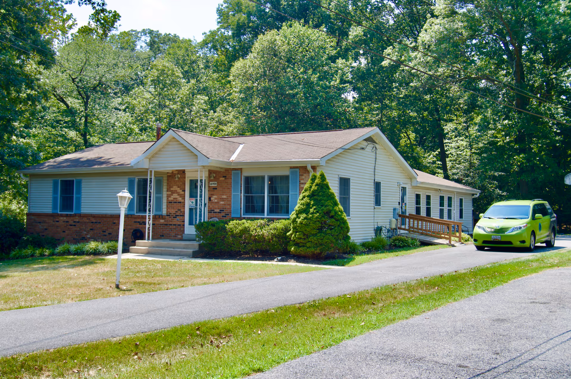 Front view of a single-story senior living facility with a lime-green car in the driveway.