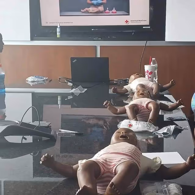 Training dolls laid on a conference table with medical equipment in a clinic-style room.