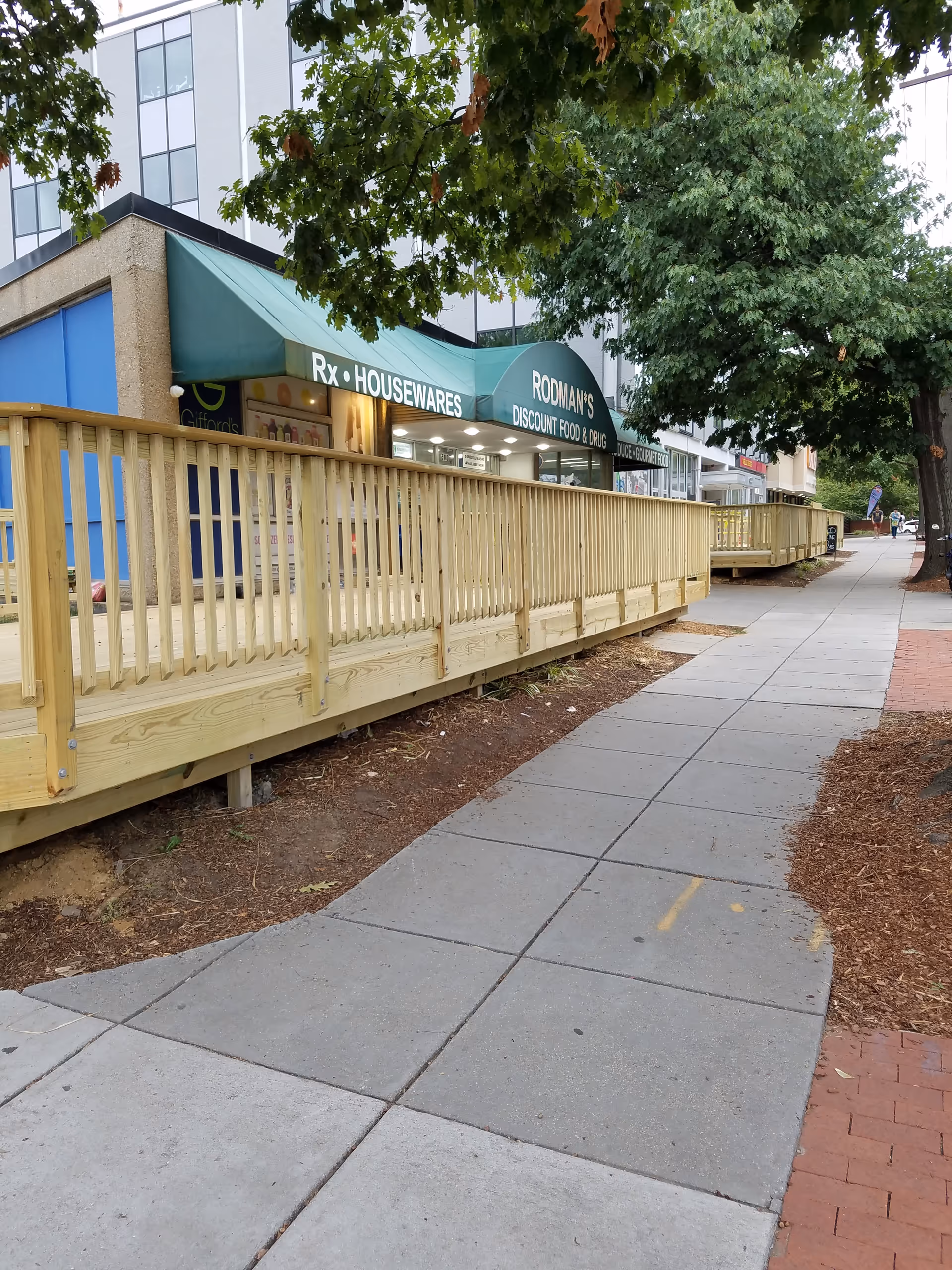 Exterior view of Rodman's storefronts along a sidewalk with a wooden railing ramp.