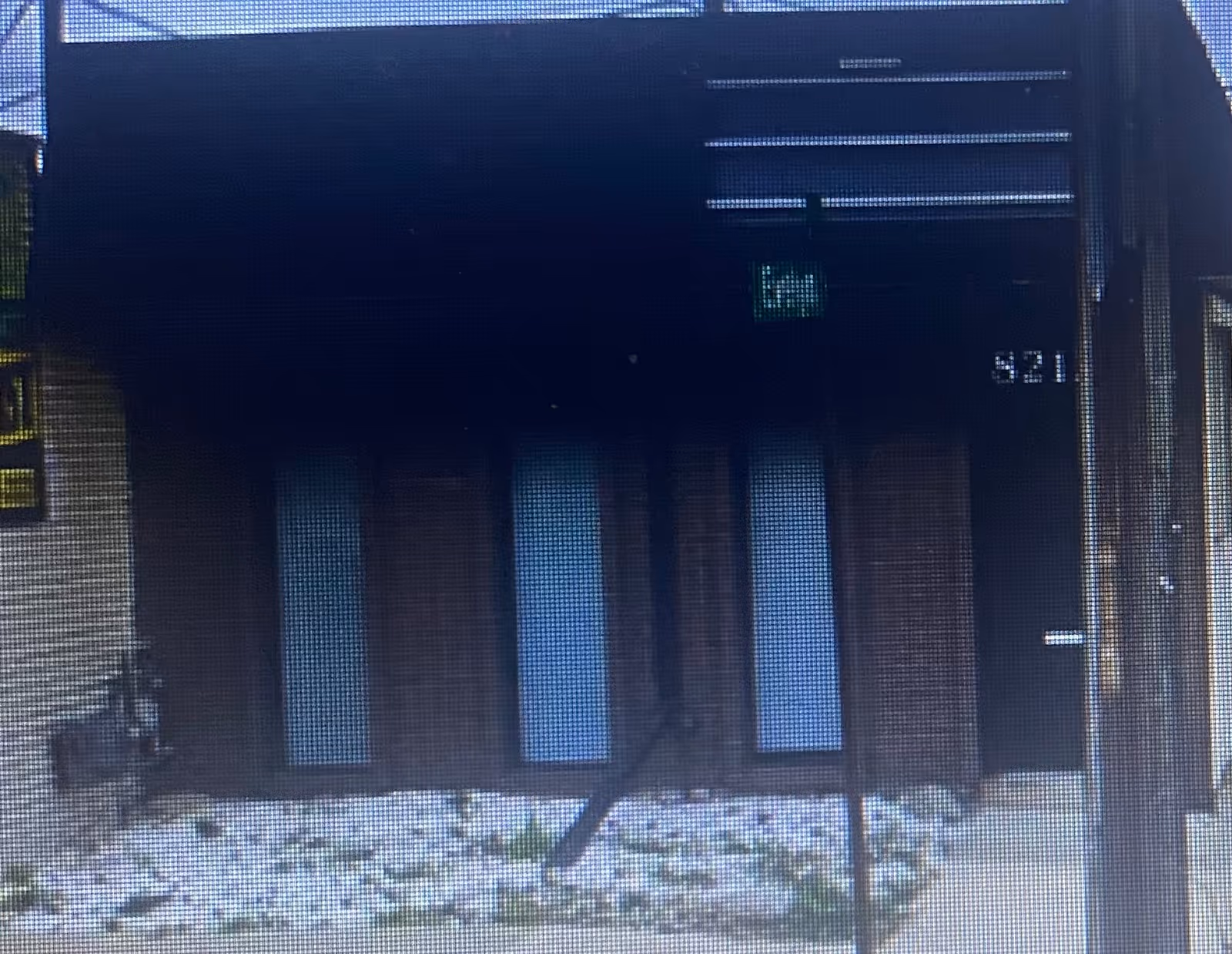 Dark modern building front with three vertical glass panels and a small exit sign.