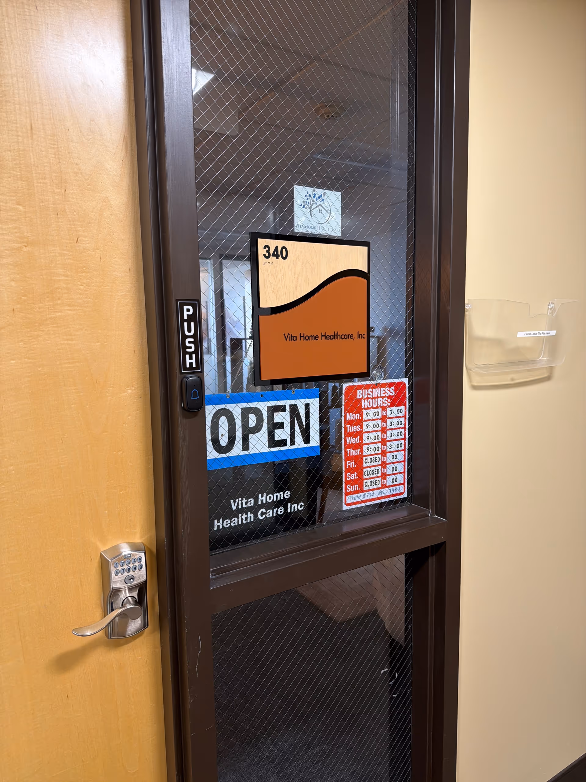 Close-up of a glass door with Vita Home Health Care signage and OPEN sign.