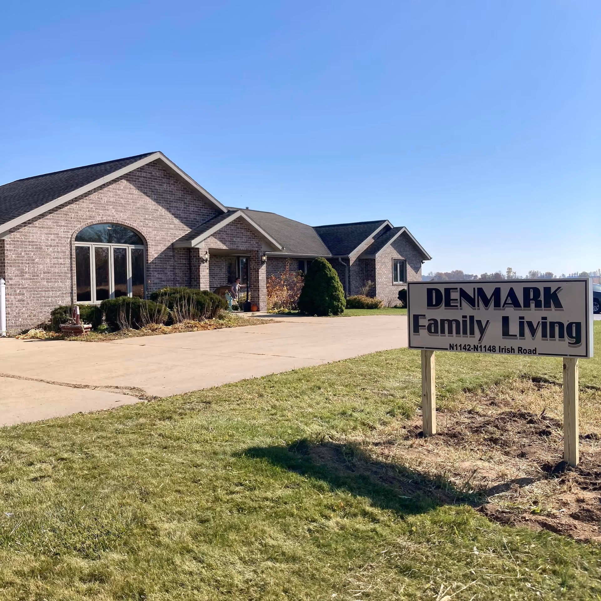 Brick senior living facility with a large sign reading Denmark Family Living in the front yard.