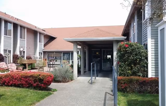 Entrance to a senior living facility with a covered walkway and landscaping.