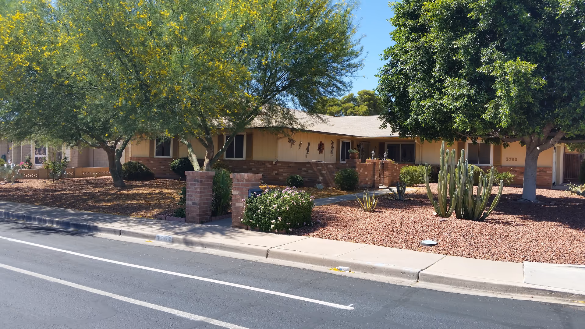 Exterior view of a single-story assisted living home with desert landscaping.