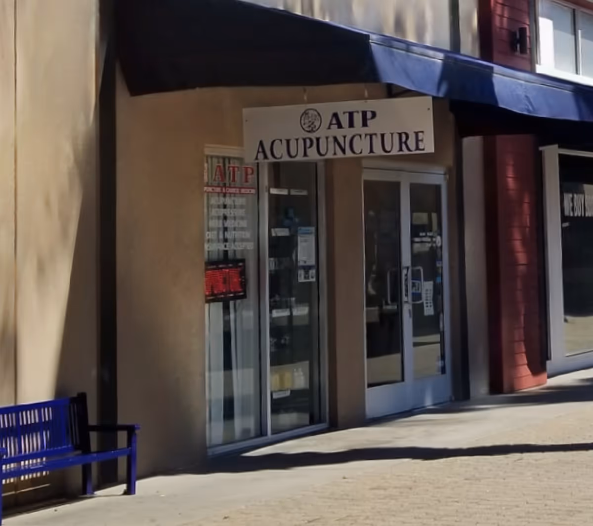 Storefront of ATP Acupuncture with glass doors and a blue awning along the sidewalk.