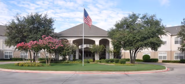 Brookdale Eden Estates senior living facility entrance with flag, trees, and landscaping.