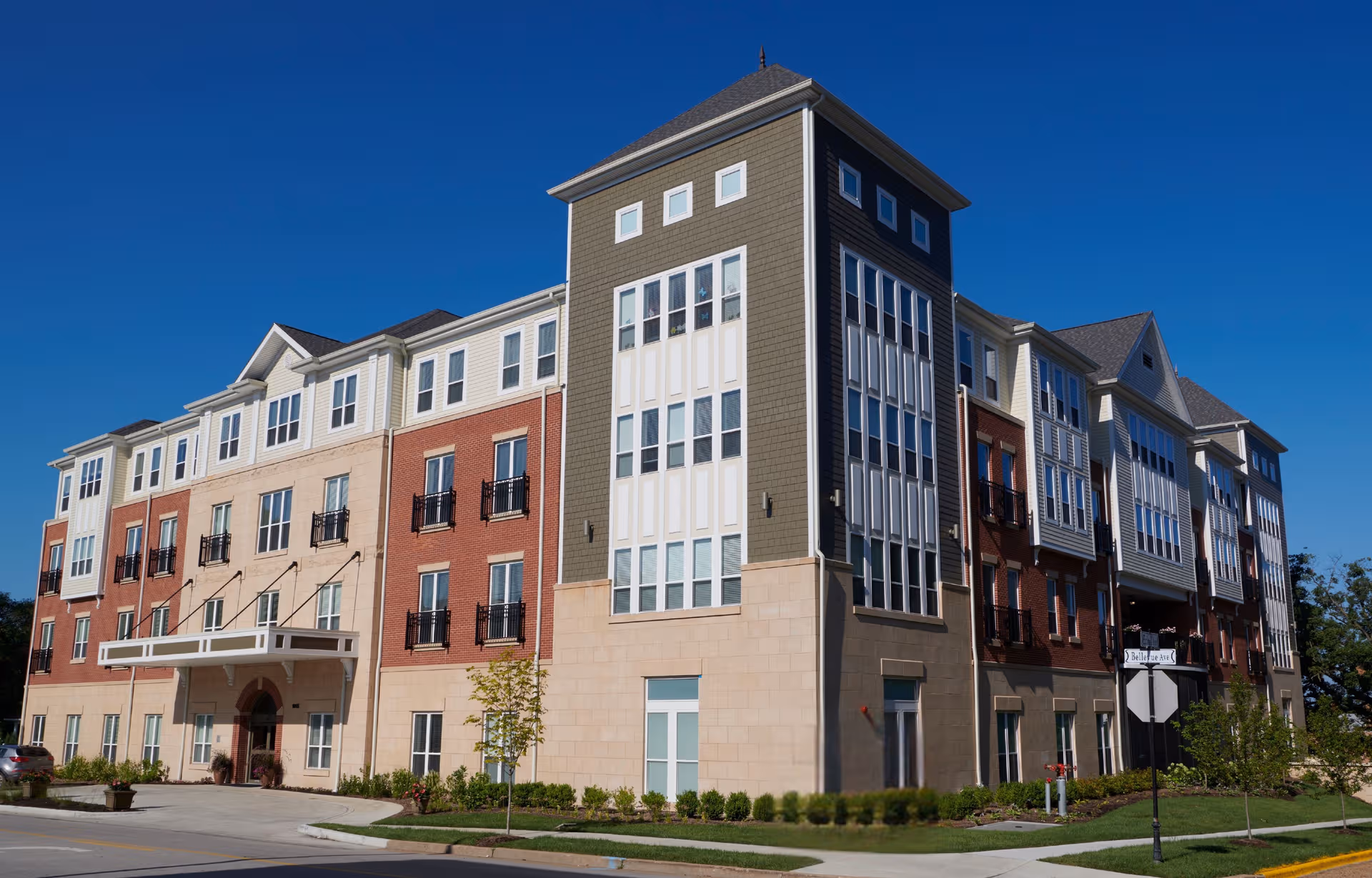 Modern multi-story senior living building exterior with varied facade colors and landscaping.