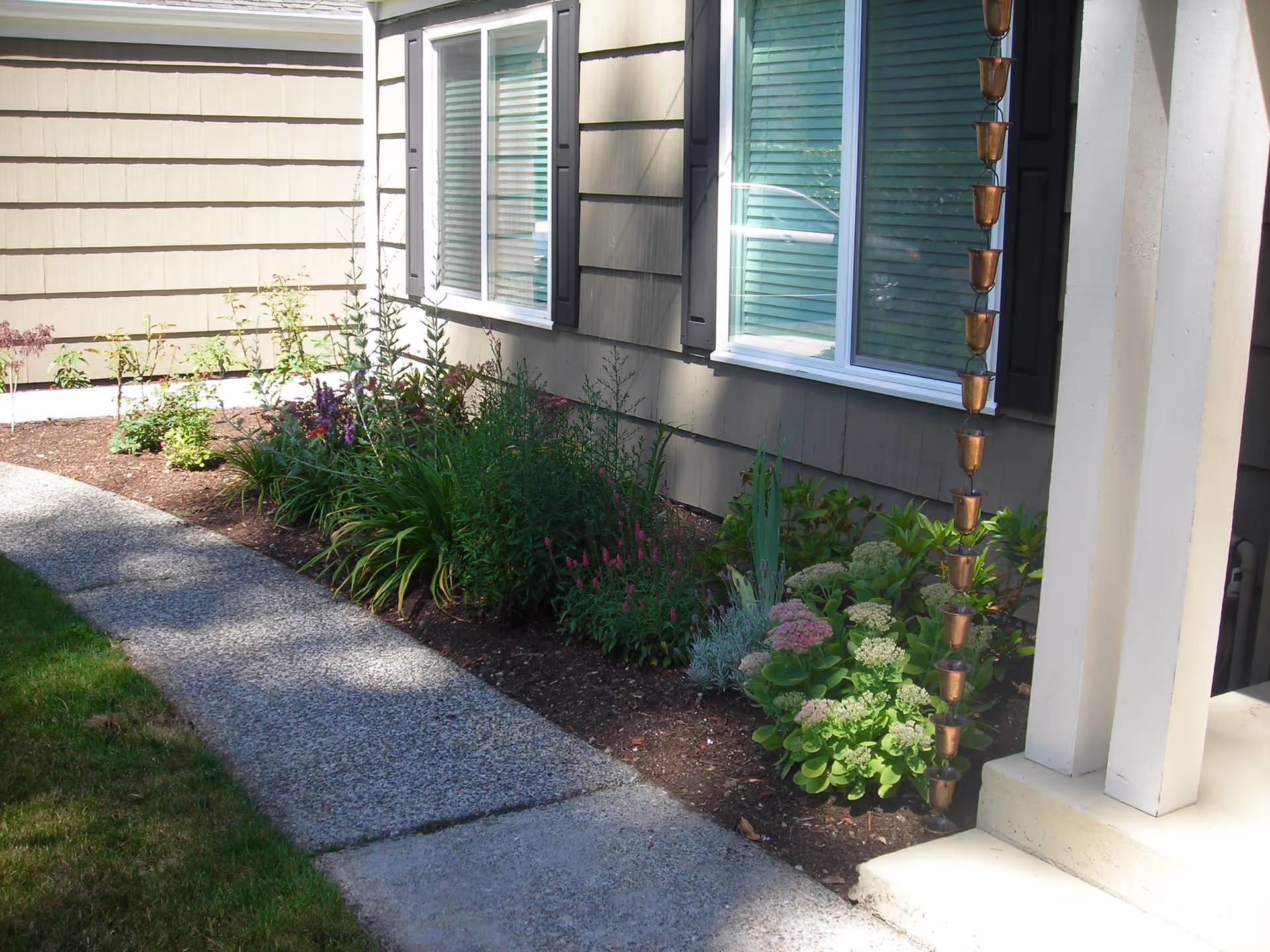Exterior of Crested Crane Adult Family Home with garden beds and a sidewalk walkway.
