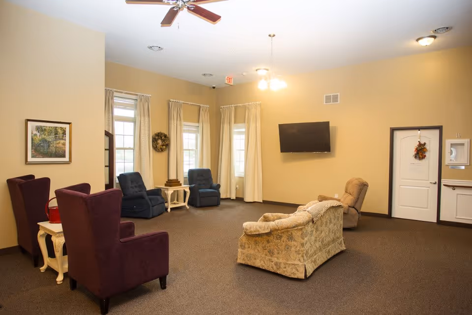Spacious beige lounge with multiple chairs and a wall-mounted TV.