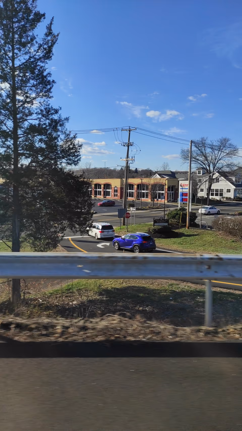 Exterior street view shows a building across a parking lot under a blue sky.