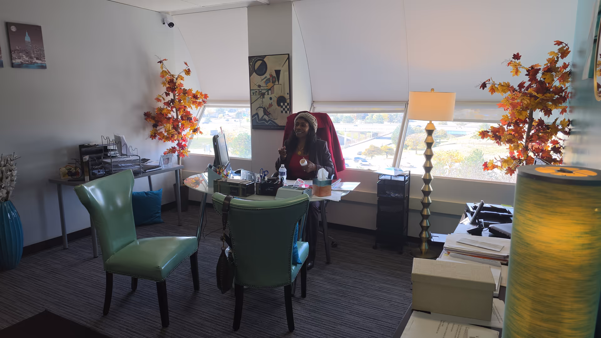 Staff member seated at a desk in a bright office with teal chairs.