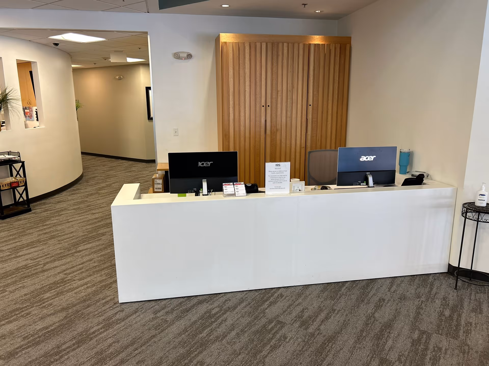 A white reception desk with two Acer monitors in a lobby area.